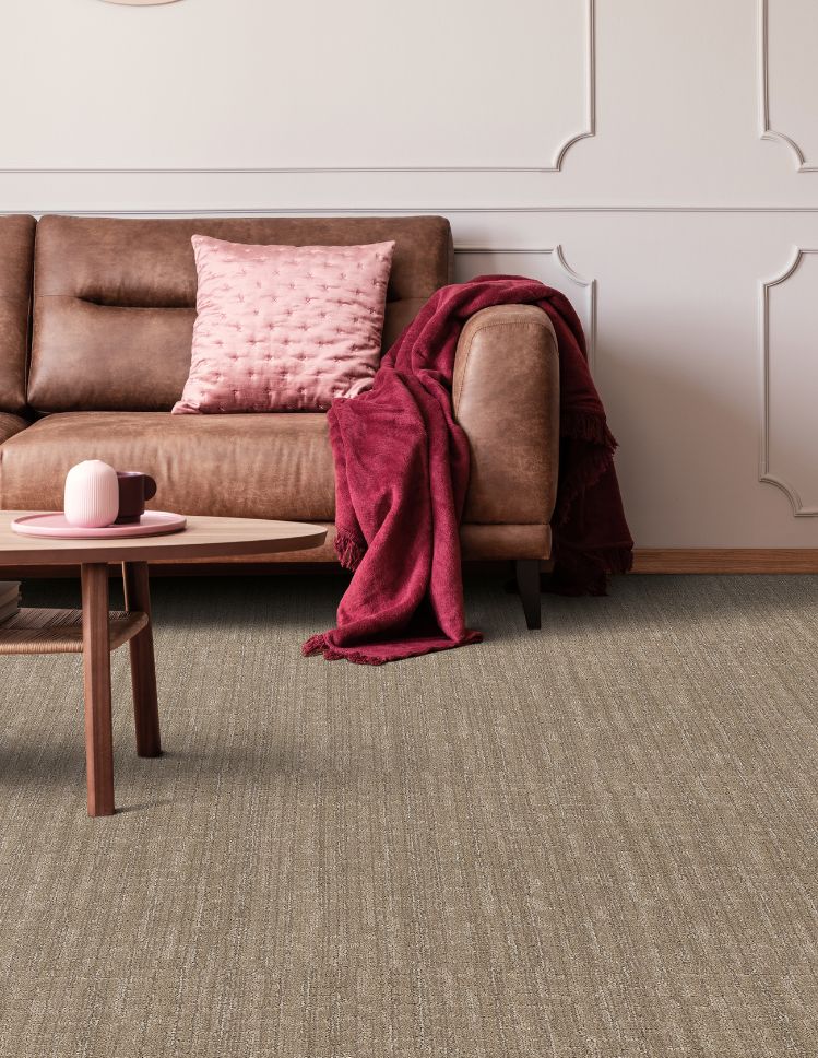textured brown carpets in a living room with brown leather couch and pink accents